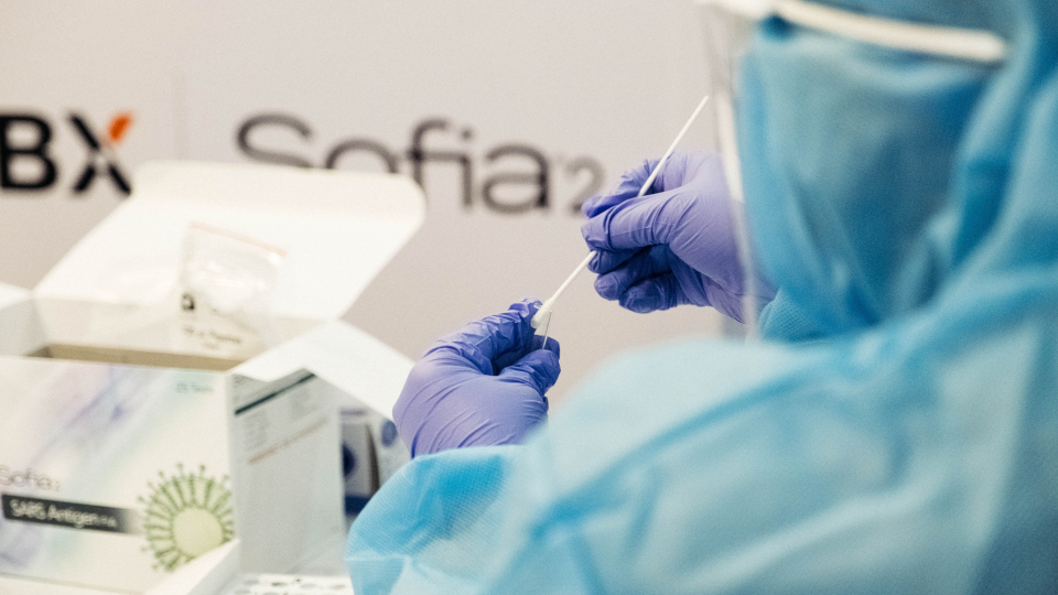 Person in Laborkleidung füllt Covid-Tests ab