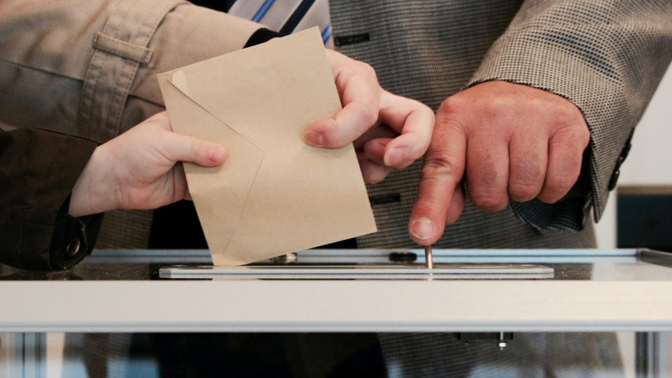 Person wirft Wahlschein in Urne