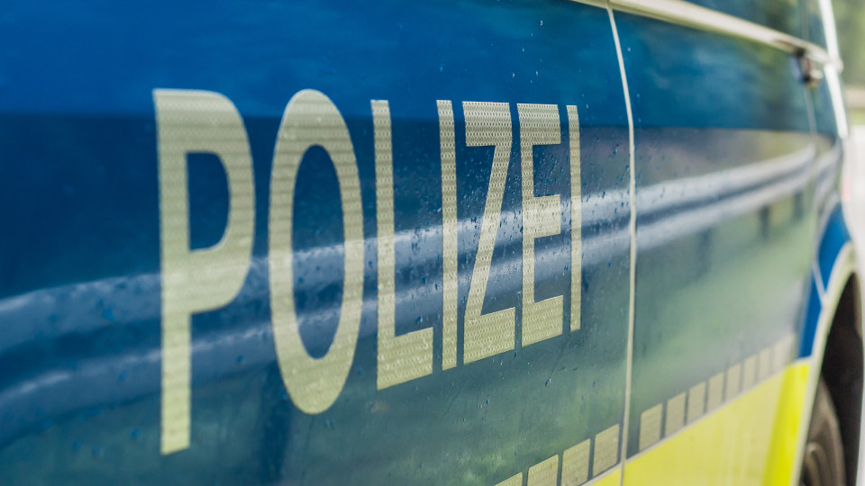 Streifenwagen der Polizei, der gerade am Fahrbahnrand steht, von der Seite: Schriftzug POLIZEI im Vordergrund.