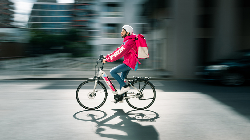 Flink Fahrer auf Fahrrad mit pinker Jacke