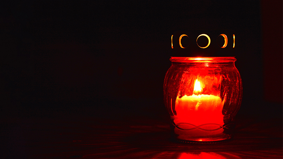 Brennende Grabkerze vor schwarzem Hintergrund