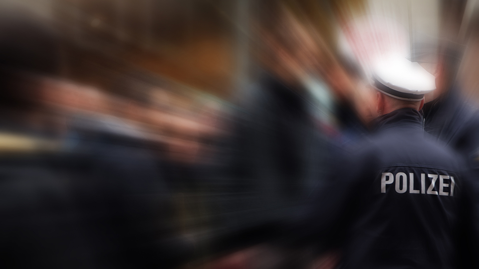 Polizist von hinten mit Schriftzug "Polizei" auf dem Rücken der Uniform