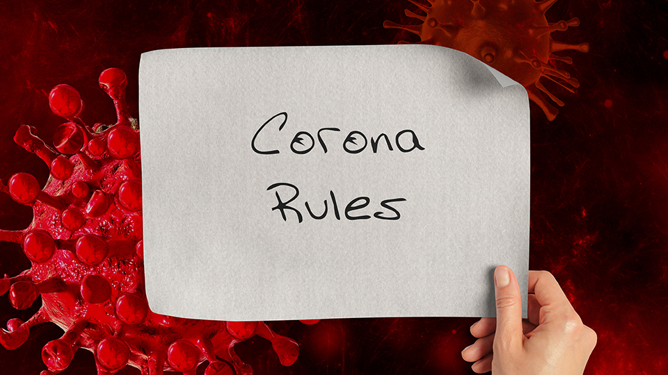 Corona-Virus im Hintergrund und davor ein Schild auf dem steht: "Corona Rules"