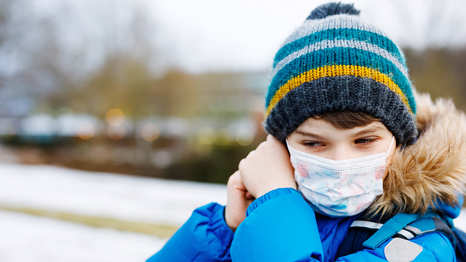 Kleiner Junge mit Maske und Mütze