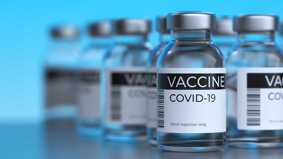 Zahlreiche Covid 19-Impfungen hintereinander aufgestellt mit blauem Hintergrund.
