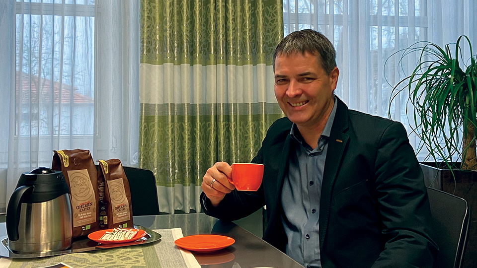Bürgermeister Schindler sitzt am Tisch und genießt den neuen fairgehandelten Oherrn-Kaffee