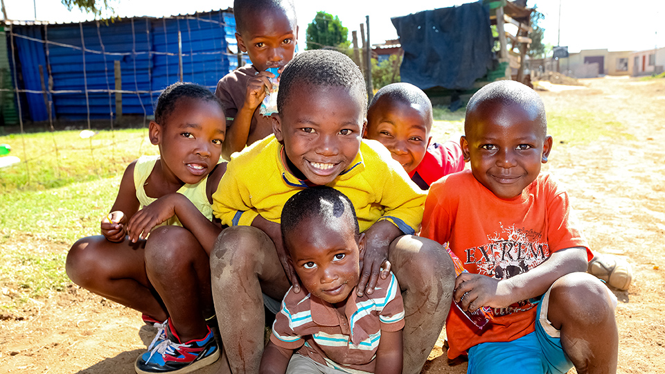 Sechs Mädchen und Jungen aus Afrika schauen lächelnd in die Kamera. Sie tragen helle Farben.