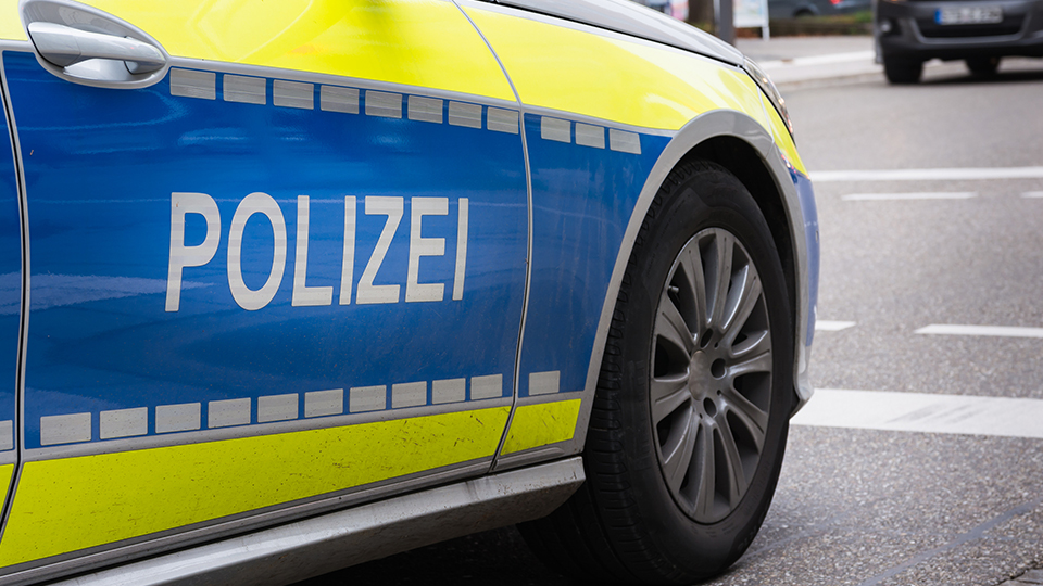 Polizeiauto von der Seite: Schriftzug POLIZEI im Vordergrund.