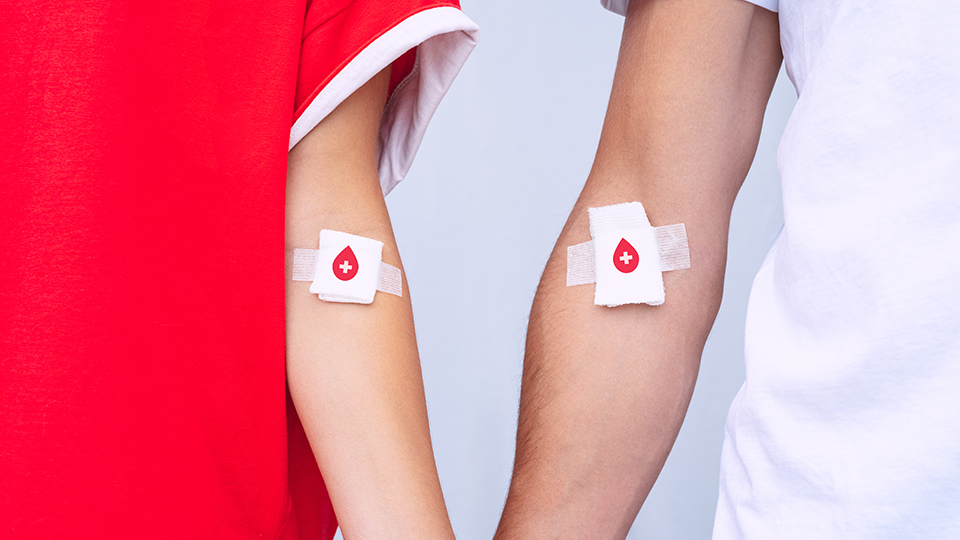 Zwei Arme mit Pflastern auf der Innenseite, die auf eine Blutabnahme hinweisen. Auf beiden Pflastern befindet sich ein Herz.