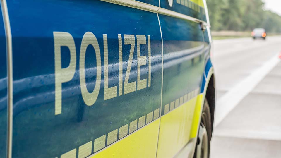 Ein Streifenwagen der Polizei von der Seite, wie er am Straßenrand steht, mit dem Schriftzug "POLIZEI" im Fokus.
