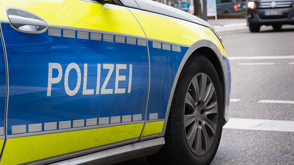 Polizeiauto von der Seite: Schriftzug POLIZEI im Vordergrund.