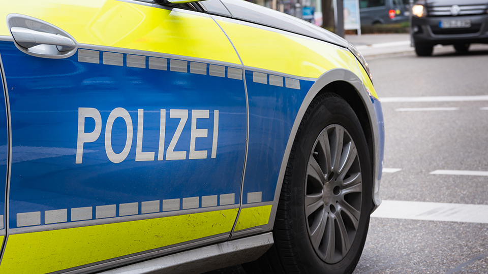 Streifenwagen der Polizei von der Seite, der Schriftzug "POLIZEI" ist dabei im Vordergrund.