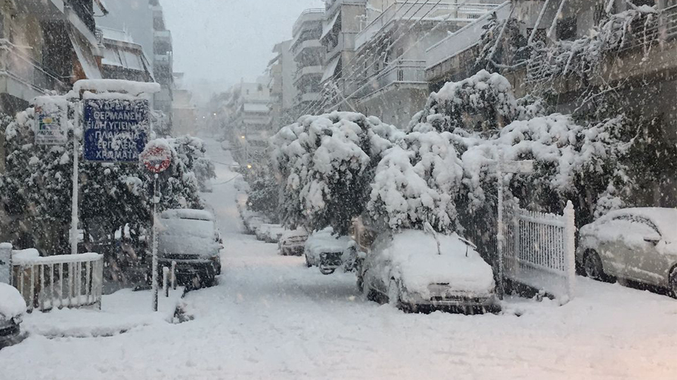 Bild vom Wintereinbruch in Athen - Gebäude, Autos und Straßen liegen unter einer hohen Schneedecke.
