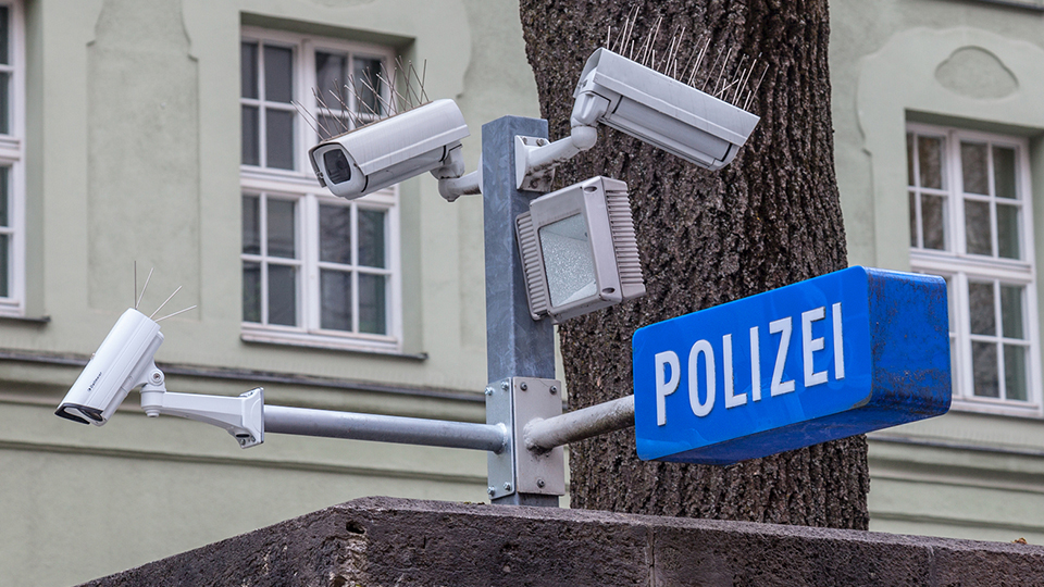 Polizei Schild in Blau-Weiß und Überwachungskameras.