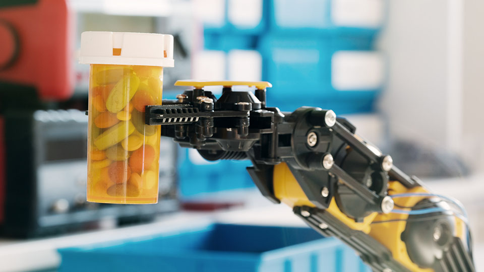 Ersatz für Pflegekraft: Roboter-Arm, der einen Behälter mit Tabletten hält.