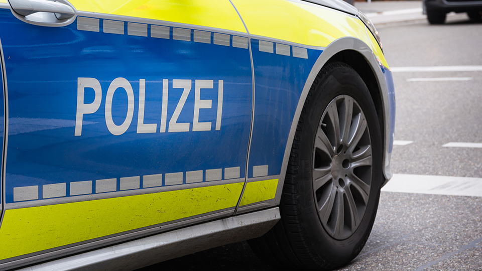 Streifenwagen der Polizei von der Seite, der Schriftzug "POLIZEI" ist dabei im Vordergrund.