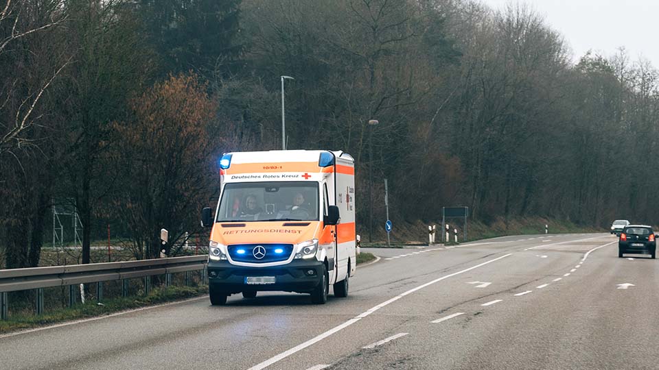 Krankenwagen mit Blaulicht während der Fahrt von vorne.