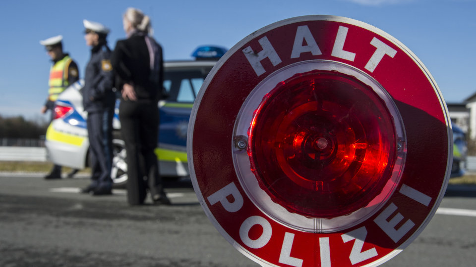 Polizeikelle im Vordergrund, Streifenwagen im Hintergrund