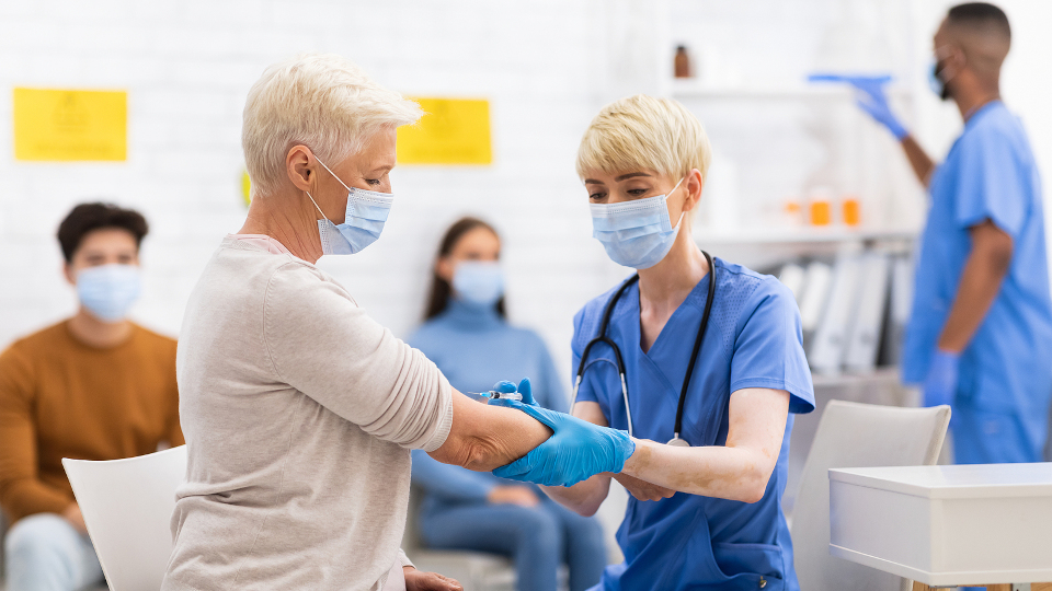 Ältere Frau wird von junger Ärztin geimpft