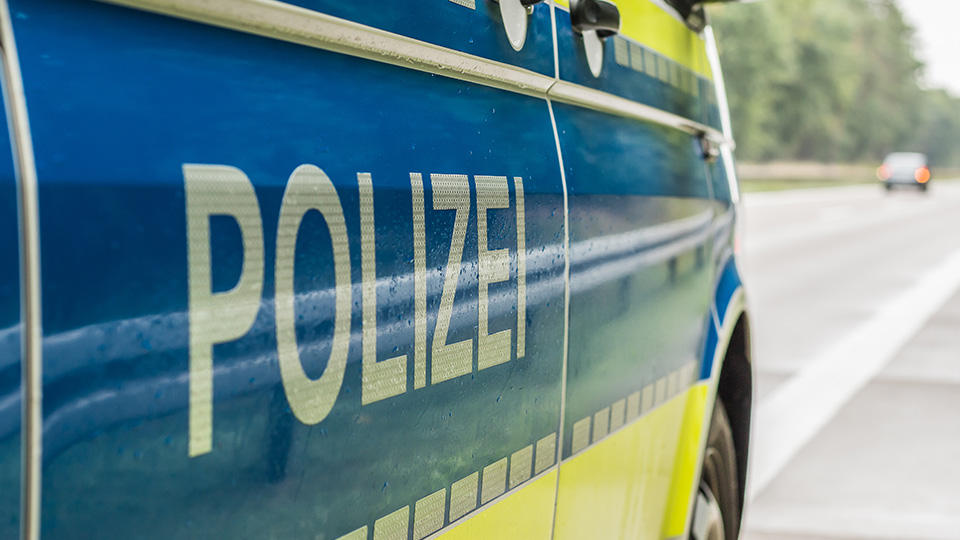 Streifenwagen der Polizei von der Seite. Schriftzug POLIZEI im Vordergrund.