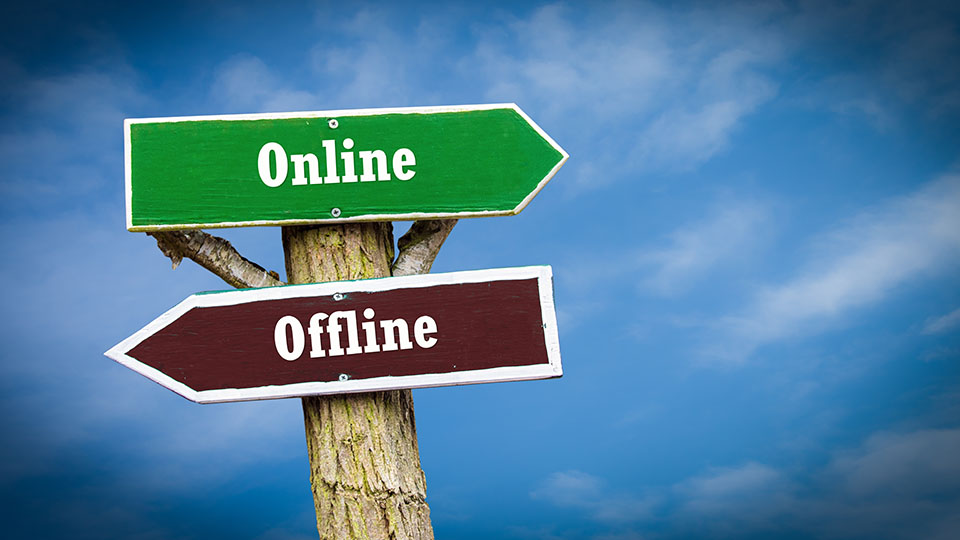 Ein grünes Straßenschild, auf dem "Online" steht, zeigt nach rechts während eine brauens Schild, auf dem "Offline" steht nach links zeigt.
