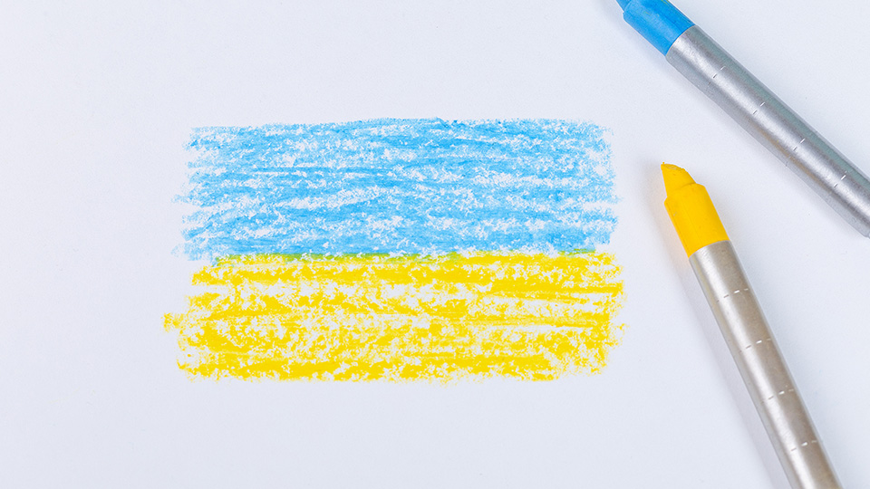 Gemalte Ukraine-Flagge, daneben Stifte in Blau und Gelb.