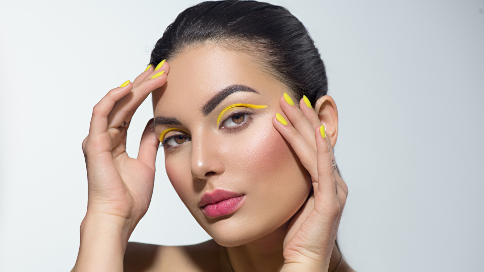 Nahaufnahme von einer jungen geschminkten Frau mit gelbem Lidstrich und natürlichem Make-up