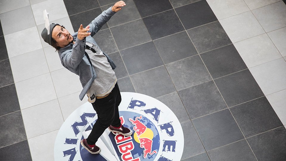 Teilnehmer der Papierflieger-Meisterschaft, wie er gerade einen Flieger in die Höhe wirft.