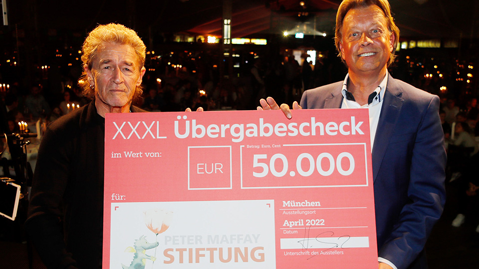 Helmuth Götz von XXXLutz (rechts) überreicht den Spendencheck in Höhe von 50.000 Euro für geflüchtete Kinder aus der Ukraine an Peter Maffay.