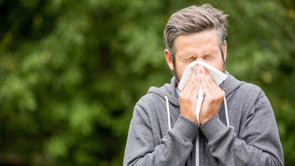 Mann schneutzt in ein Papiertuch