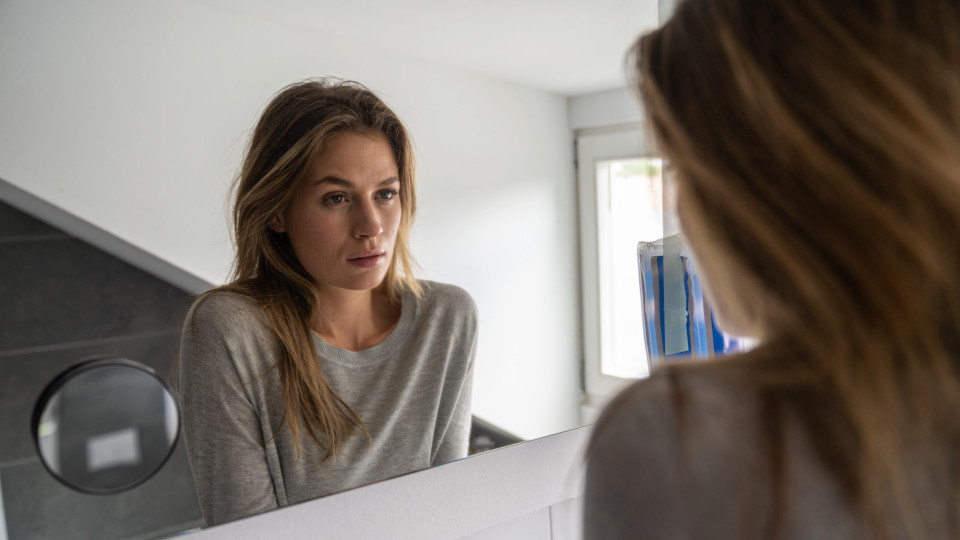 Junge Frau vor Spiegel, besorgt