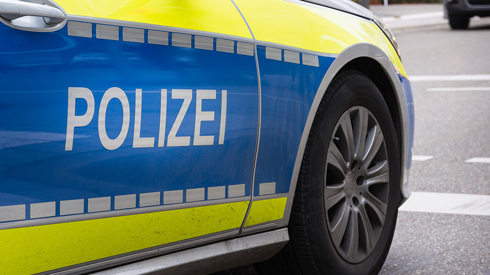 Streifenwagen der Polizei von der Seite, der Schriftzug "POLIZEI" ist dabei im Vordergrund.