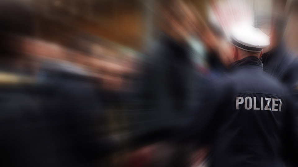 Einsatzkräfte der Polizei von hinten, wie sie gerade ein Gebäude betreten. Der Hintergrund ist unscharf.