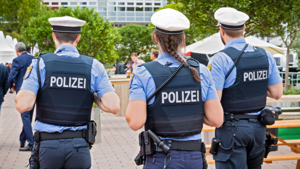 Drei Polizist:innen stehen auf einem Platz