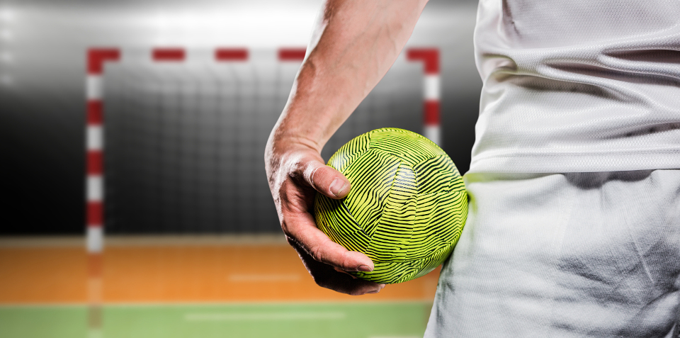 Nahaufname Handballspieler mit Handballtor im Hintergrund und Handball in der Hand