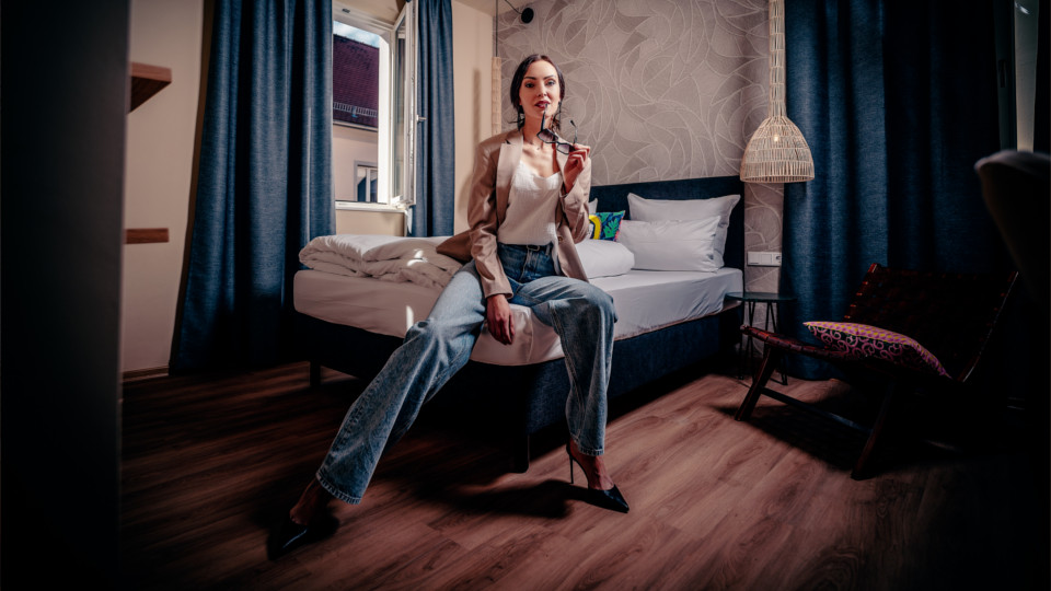 Eliska Vesela sitzt auf dem Bett im Das Regensburger Hotel