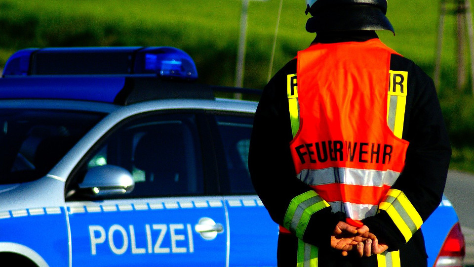 Feuerwehrmann steht vor Polizeiwagen
