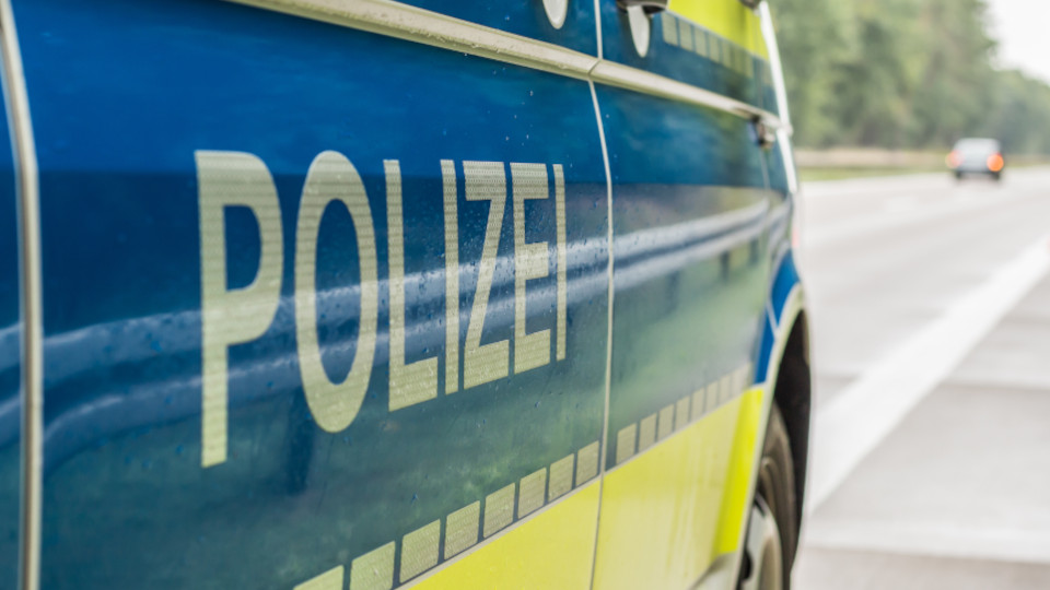 Streifenwagen der Polizei, der gerade am Fahrbahnrand steht, von der Seite: Schriftzug POLIZEI im Vordergrund.