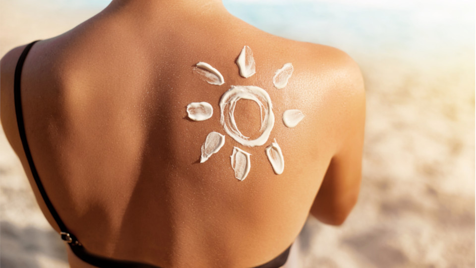 Weiblicher Rücken, auf dem Sonnencreme in der Form einer Sonne aufgetragen wurde.