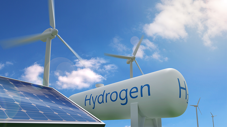 Erzeugung von Wasserstoff: Windräder, Photovoltaikanlage und Wasserstoff-Tank vor blauem Himmel.