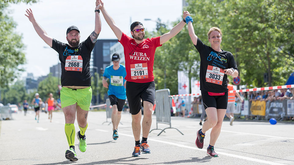 Läuferinnen und Läufer beim Regensburg Marathon machen die Siegerpose und halten sich dabei an den Händen.