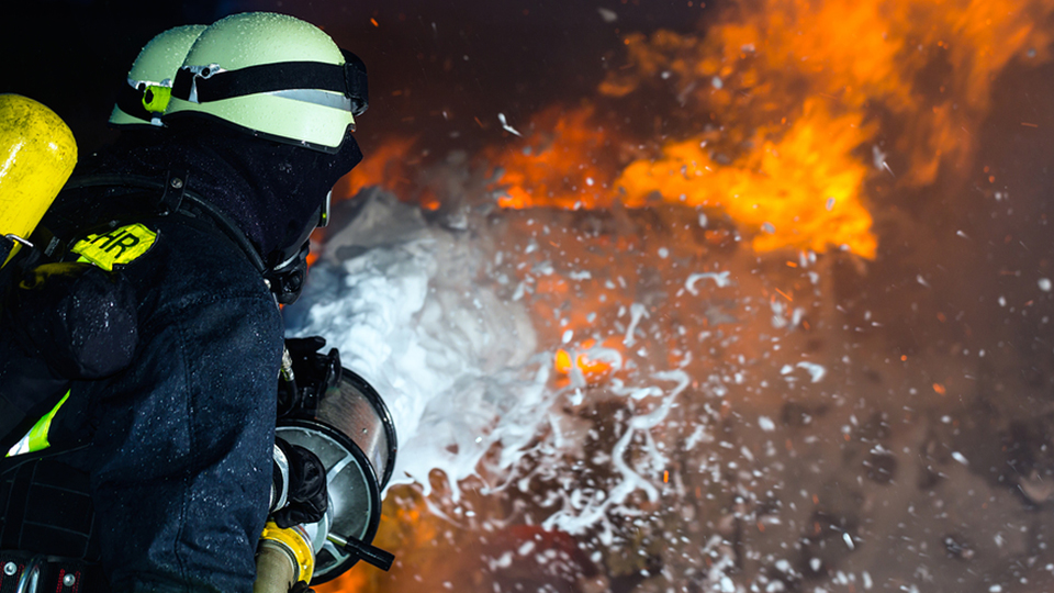 Zwei Feuerwehrmänner bekämpfen einen Brand.