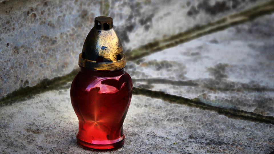 Rote Grabkerze auf einer grauen Steintreppe.