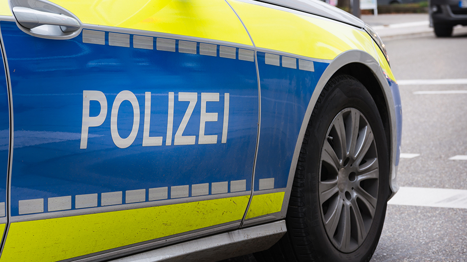 Streifenwagen der Polizei von der Seite, der Schriftzug "POLIZEI" ist dabei im Vordergrund.