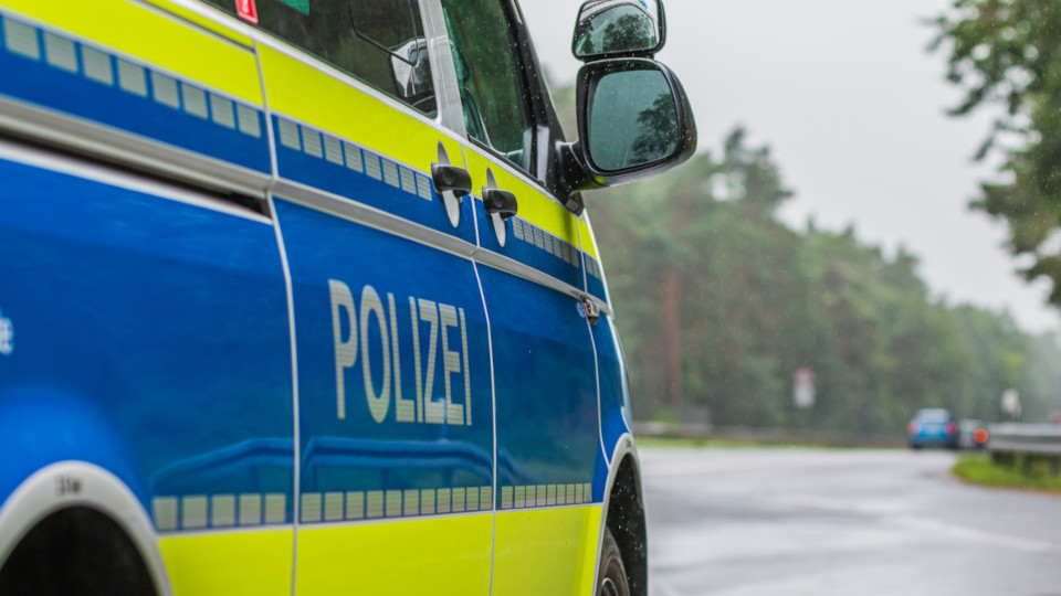 Streifenwagen der Polizei, der gerade am Fahrbahnrand steht, von der Seite: Schriftzug POLIZEI im Vordergrund.