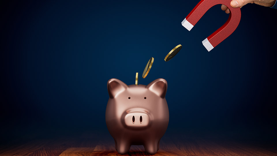 Inflation: Ein Magnet, der einem Sparschwein Geld entzieht.