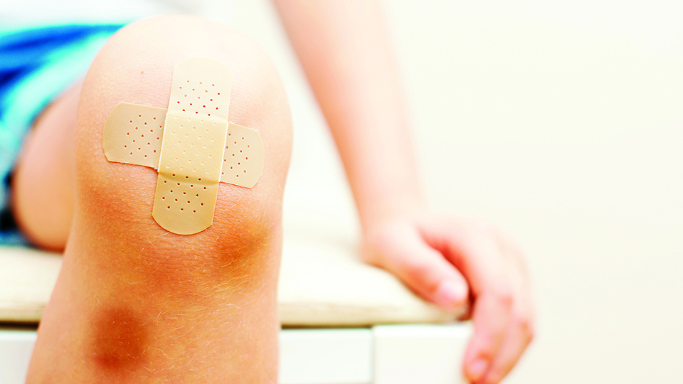 Kind mit blauen Flecken und Pflaster am Knie