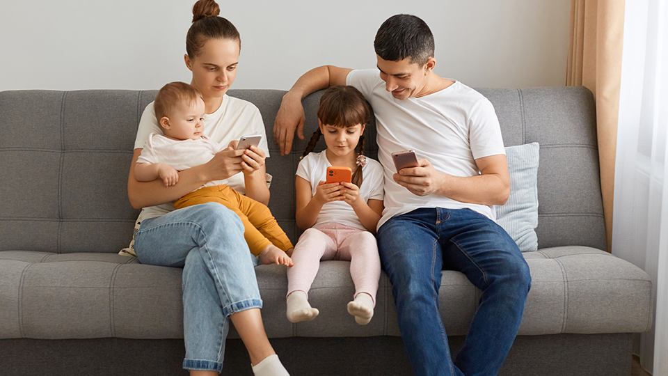 Medienkonsum bei Kindern: Eltern, die mit ihren Kindern aufs Handy schauen.