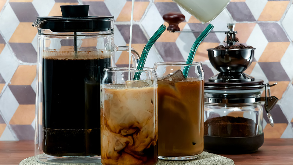 Cold Brew Coffee in zwei Gläsern mit Strohhalm, dahinter eine French Press.