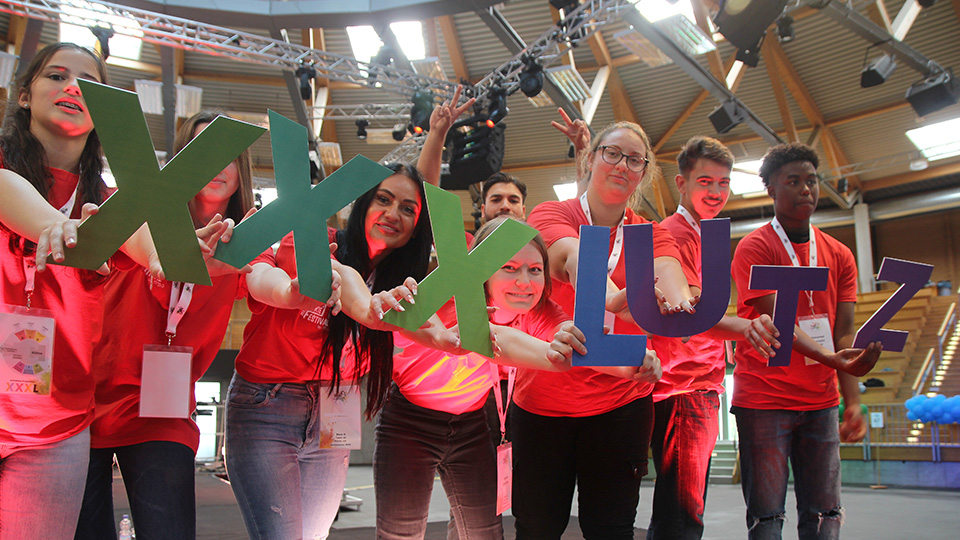 "Rookie-Festival": Die neuen Azubis von XXXLutz mit roten T-Shirts halten die Buchstaben des Schriftzugs von XXXLutz in den Händen.